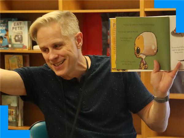  A man holds up a book as he reads it out loud.